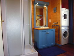 La salle d'eau; douche, lavabo, lave-linge, sèche-linge, rangement et radiateur sèche serviette.