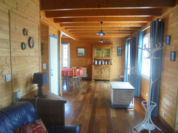 Vue du salon vers le coin cuisine avec une porte-fenêtre pour accéder à la terrasse.